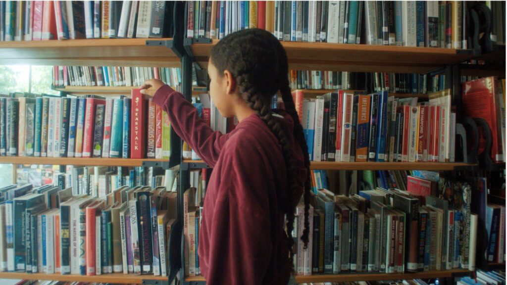 A girl is choosing a book from a shelf in the library